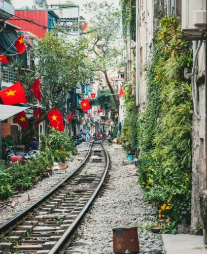 Ruelle étroite à Hanoï, avec une voie ferrée et des maisons colorées.