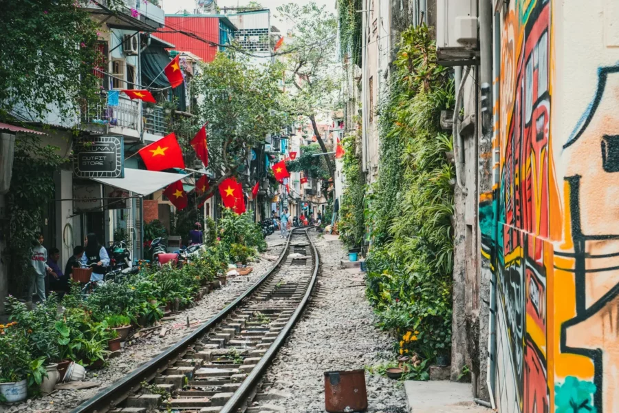 Ruelle étroite à Hanoï, avec une voie ferrée et des maisons colorées.
